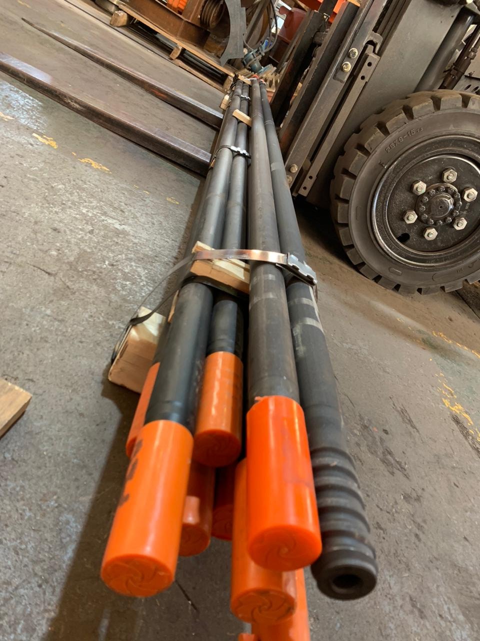 Drill rods with orange end caps bundled and ready for client delivery